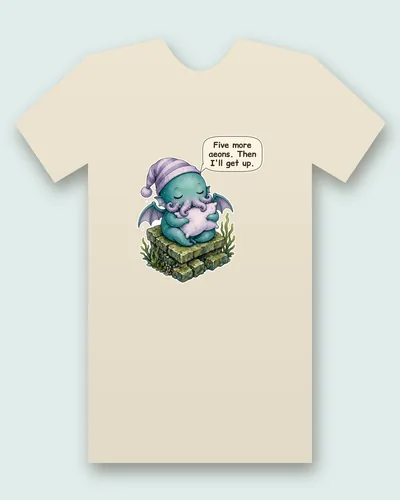 Deep Sea Dreamer tee mockup: a sleepy teal sea creature with tiny bat-like wings, in a striped lavender nightcap, hugging a pillow on a mossy sunken stone ruin with swaying seaweed, saying “Five more aeons. Then I'll get up.”