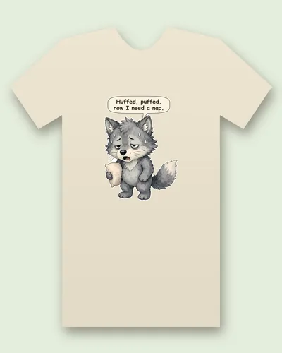 Huffing Puffing Wolf tee mockup: a fluffy grey wolf, droopy-eyed and sweating, hugging a pillow with his bushy tail drooping, saying “Huffed, puffed, now I need a nap.”