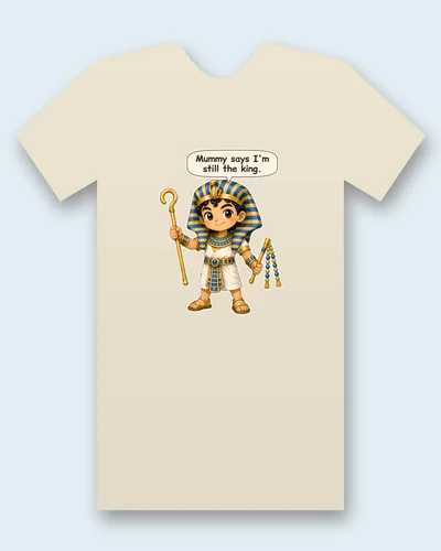 King Tutankhamun tee mockup: King Tutankhamun in a blue and gold striped headdress, holding a crook up in one hand and a beaded flail in the other, saying “Mummy says I'm still the king.”