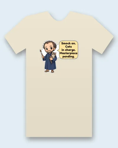Gustav Klimt tee mockup: Gustav Klimt with curly hair and a beard, in a long blue painter's smock and sandals, holding a paintbrush and a fluffy grey tabby kitten, saying “Smock on. Cats in charge. Masterpiece pending.”