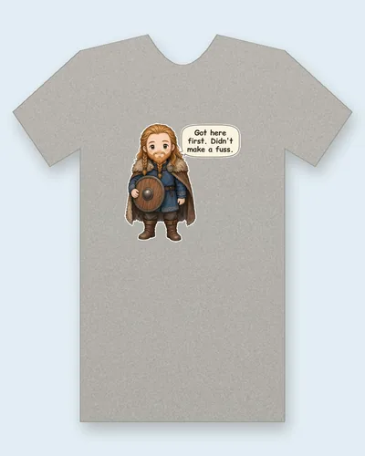 Leif Erikson tee mockup: Leif Erikson, the Norse explorer, in a blue wool tunic and fur-trimmed cloak, with a braided beard and a round wooden shield, saying “Got here first. Didn't make a fuss.”