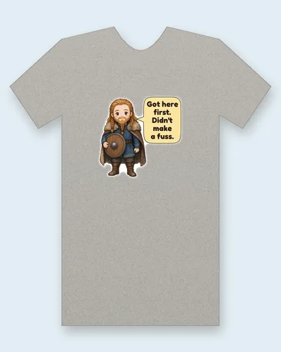 Leif Erikson tee mockup: Leif Erikson, the Norse explorer, in a blue wool tunic and fur-trimmed cloak, with a braided beard and a round wooden shield, saying “Got here first. Didn't make a fuss.”