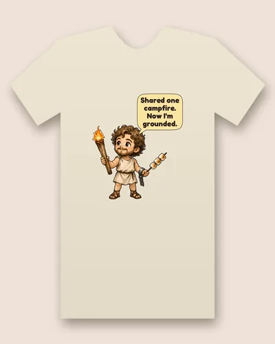 Prometheus tee mockup: A curly-haired young man in a simple tunic and sandals holding a flaming torch, with a broken chain on one wrist and marshmallows on a stick, and a speech bubble above him, saying “Shared one campfire. Now I'm grounded.”