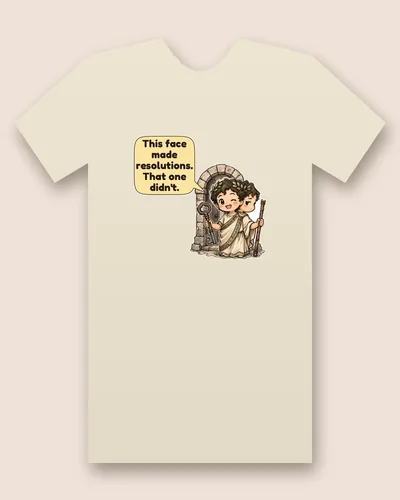 Roman God of January tee mockup: A young two-faced Roman in a laurel wreath and white toga, holding a large iron key and a staff in front of an arched stone door, with a speech bubble beside him, saying “This face made resolutions. That one didn't.”