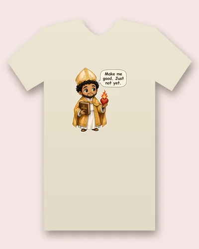 Saint Augustine of Hippo tee mockup: a bishop with curly black hair and a short beard, in a gold mitre and embroidered vestments, holding a book and a flaming heart, saying “Make me good. Just not yet.”
